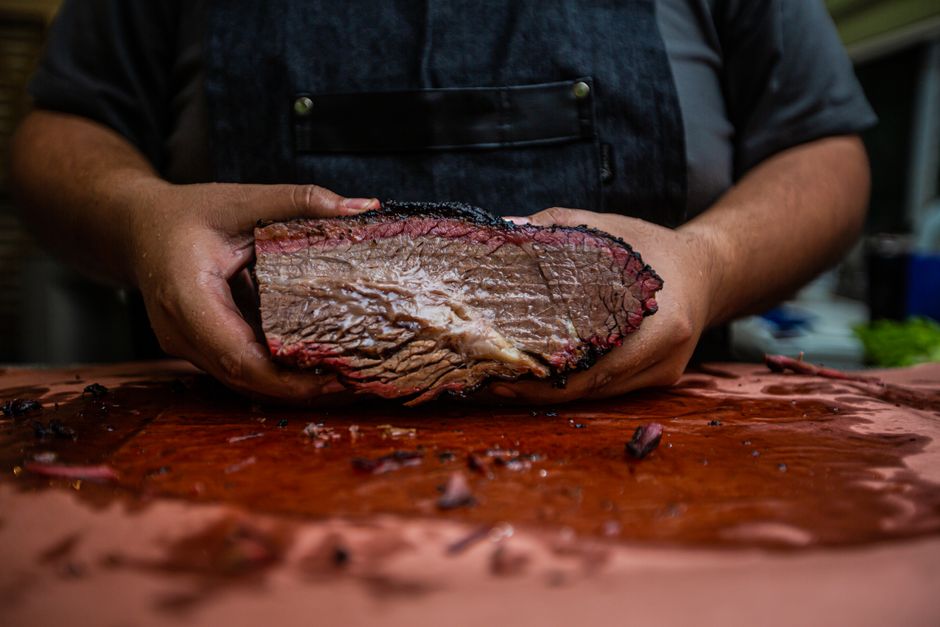 Pitmaster presenting a whole smoked brisket half