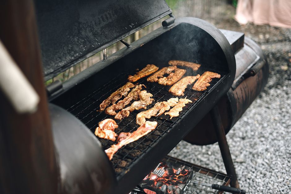 Offset smoker with visible smoke and meat on the grates