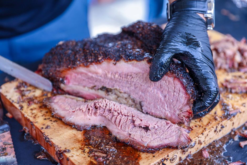 Gloved hand slicing brisket with dramatic light